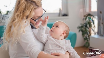 Mother holding a baby while multitasking at work